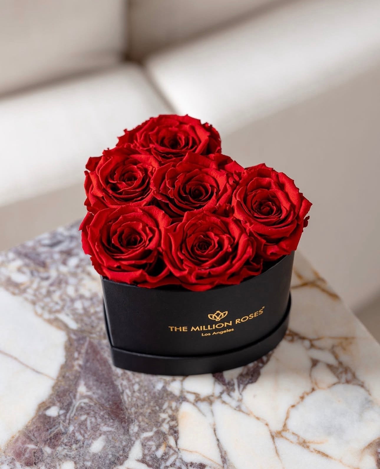 Heart-shaped box with red roses on a calacutta viola marble surface, featuring 'The Million Roses' brand.